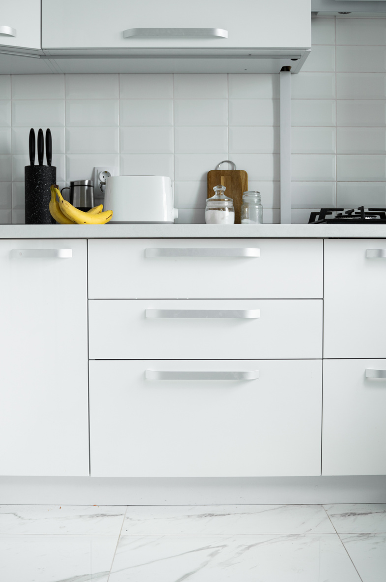 White lacquered kitchen facades on a comfortable kitchen. Modern white kitchen clean interior design.